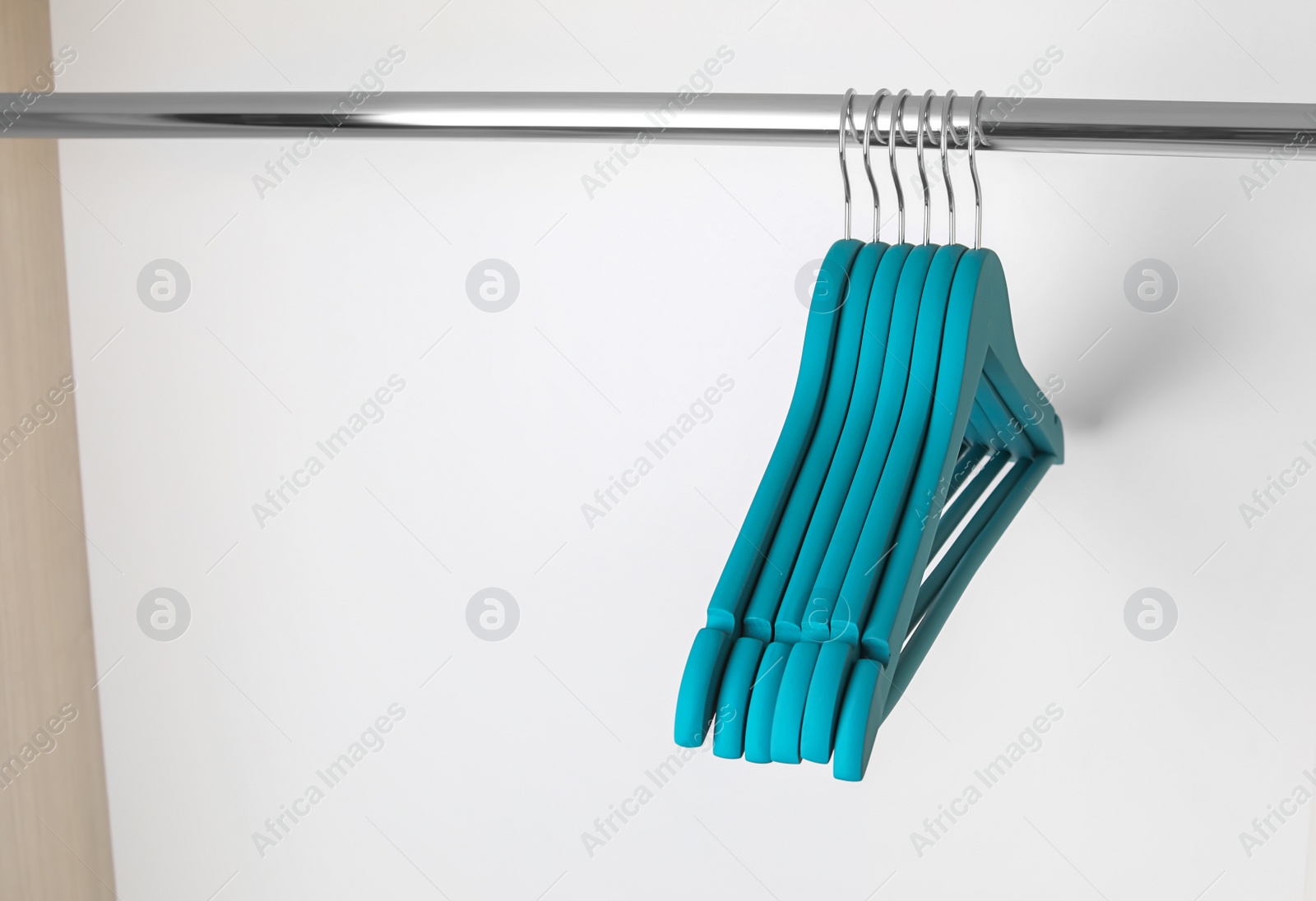 Photo of Clothes hangers on metal rail in wardrobe