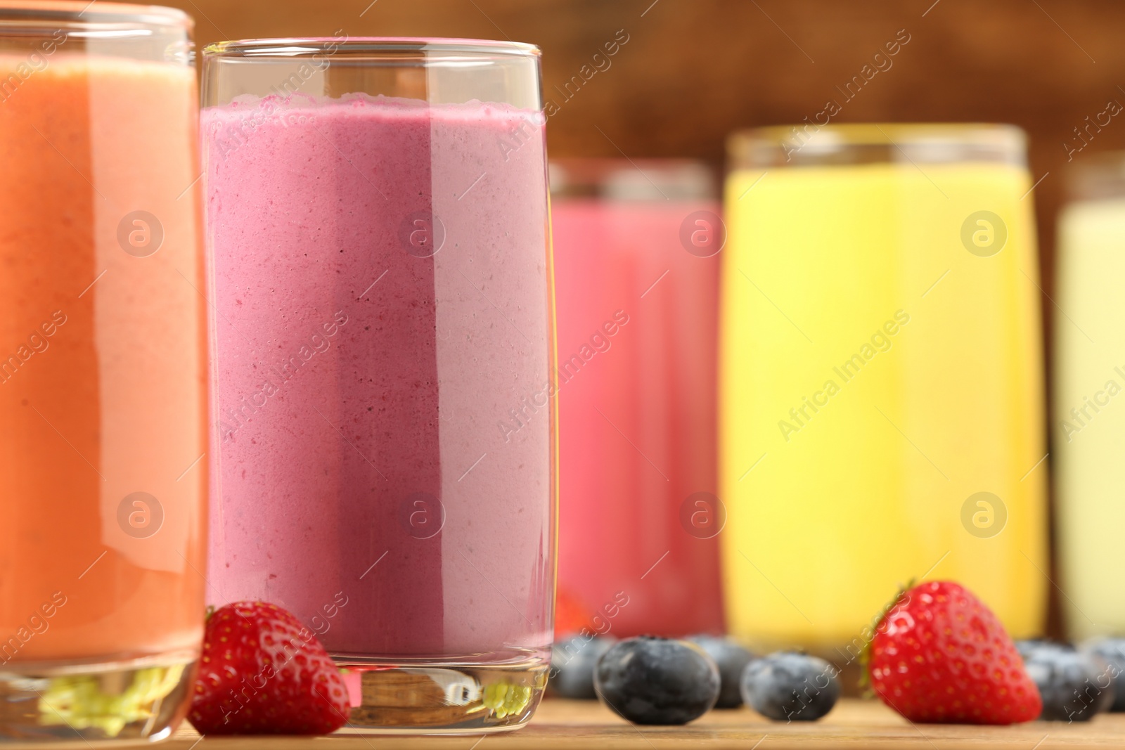 Photo of Glasses with different tasty smoothies on wooden table, closeup