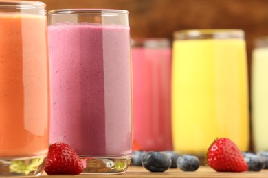 Glasses with different tasty smoothies on wooden table, closeup