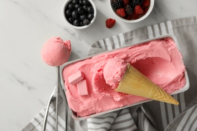 Photo of Delicious ice cream in container and wafer cone on white marble table, flat lay