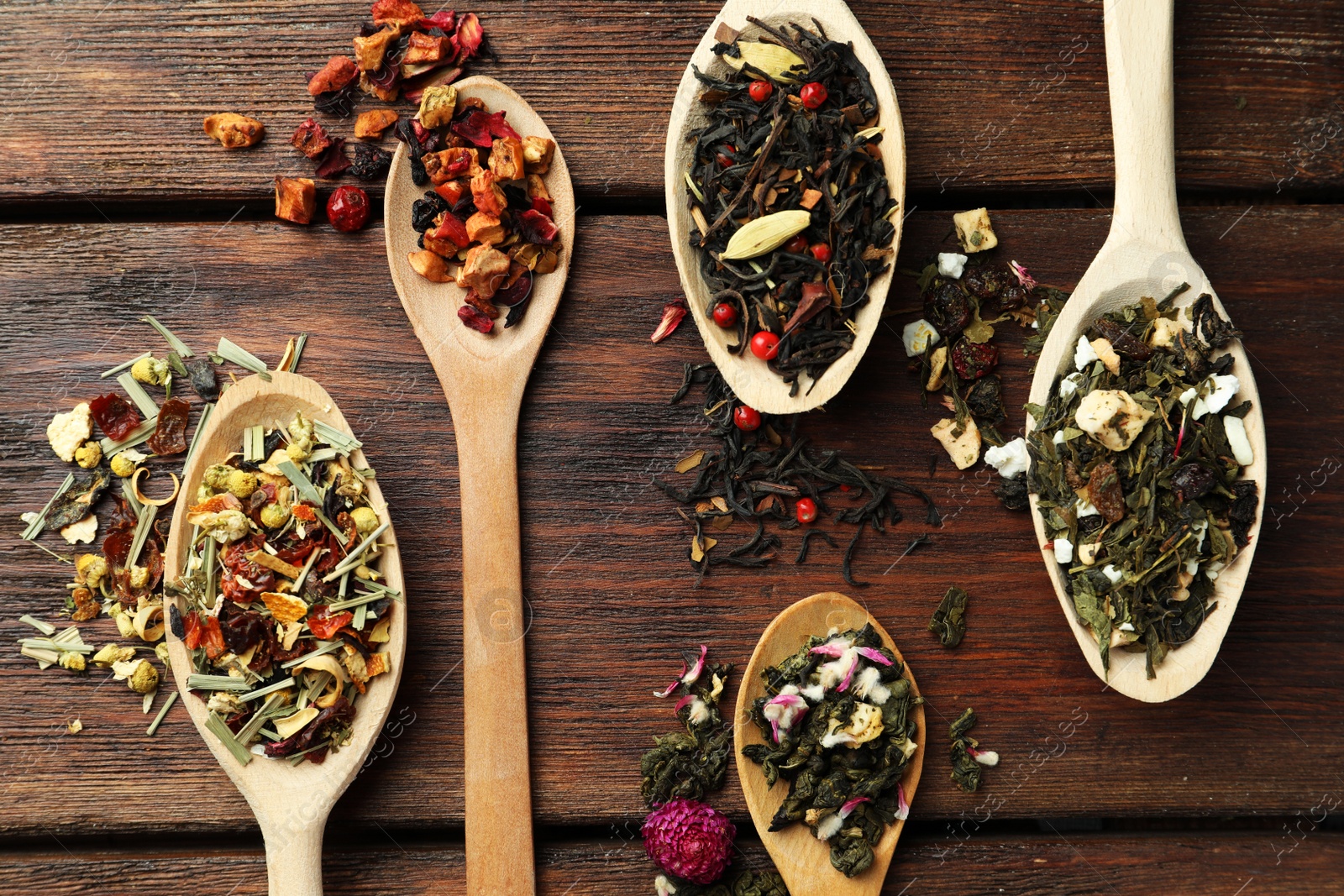 Photo of Flat composition with spoons of dried herbal tea leaves on wooden table