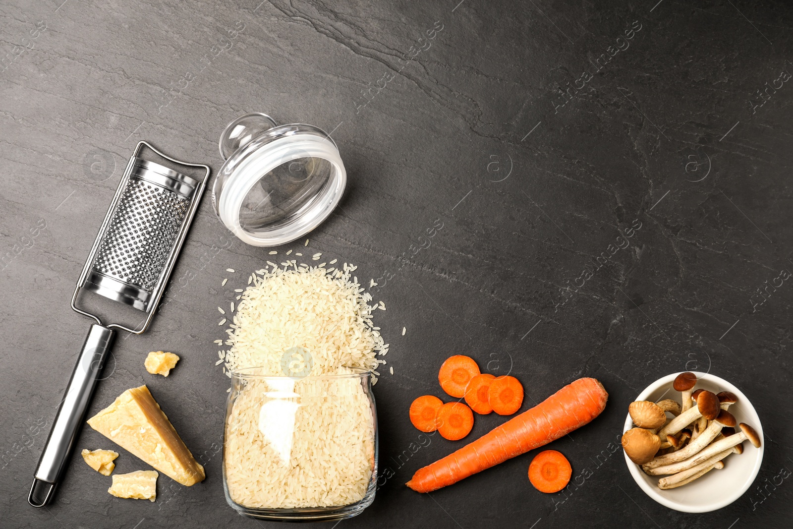 Photo of Flat lay composition with different ingredients on black table, space for text. Risotto recipe