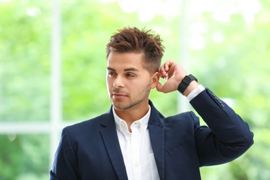 Portrait of handsome young man in elegant suit against window