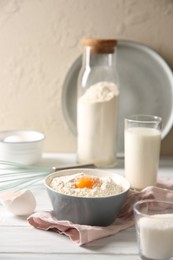 Photo of Making dough. Flour with yolk in bowl on white wooden table