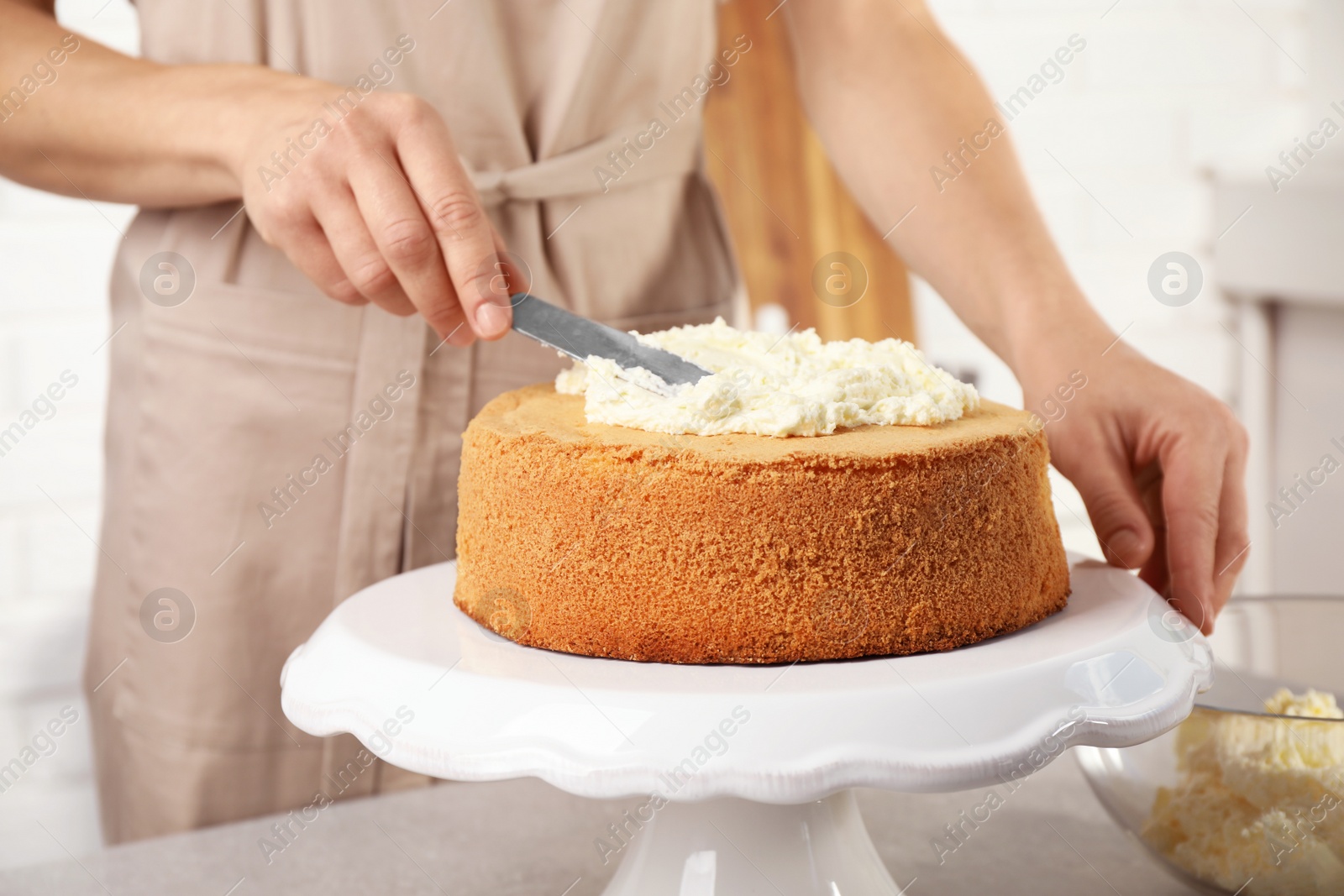 Photo of Woman decorating delicious cake with fresh cream at table indoors, closeup. Homemade pastry