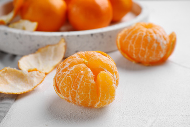 Photo of Peeled ripe tangerine on white table, closeup