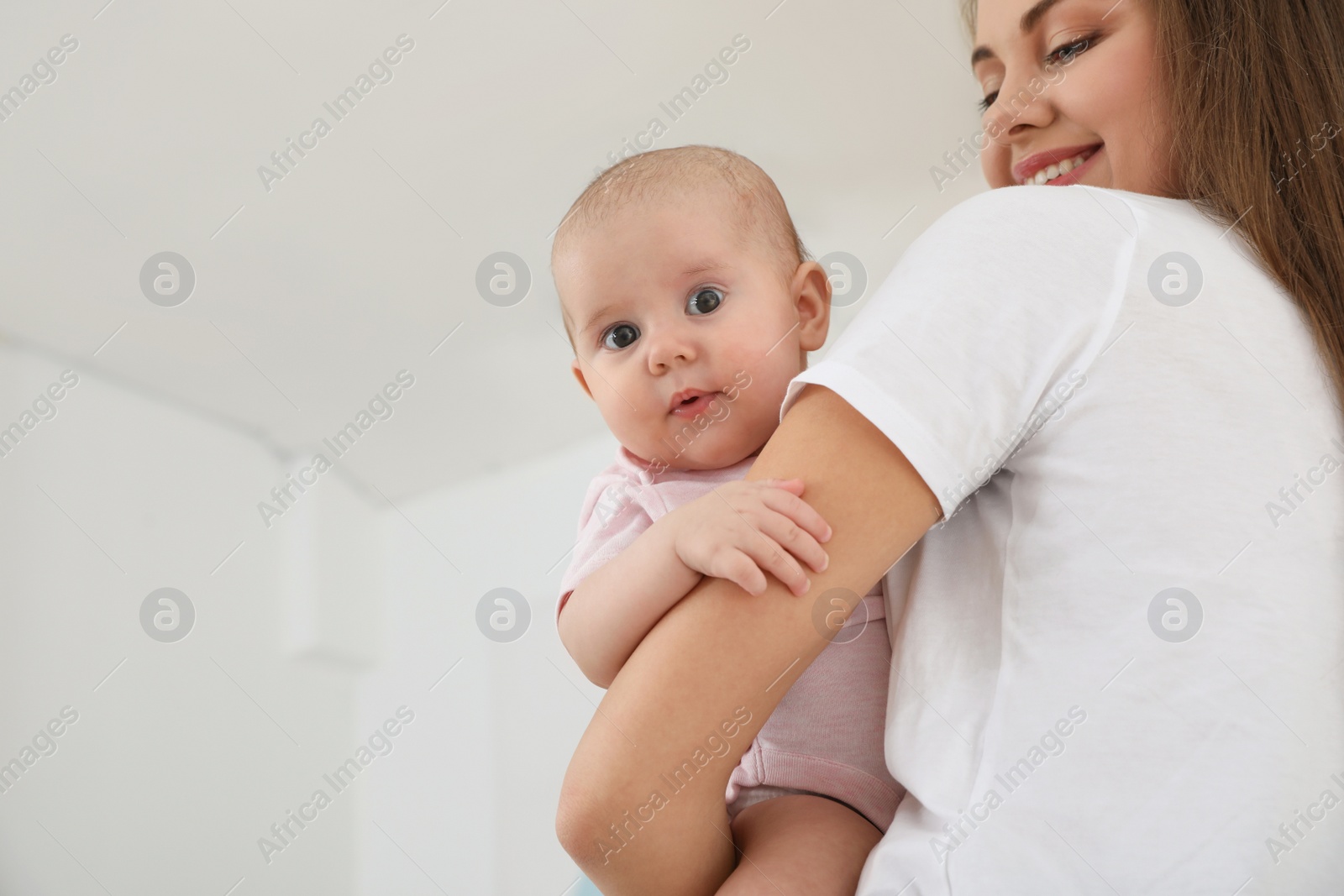 Photo of Mother holding her adorable baby indoors. Space for text