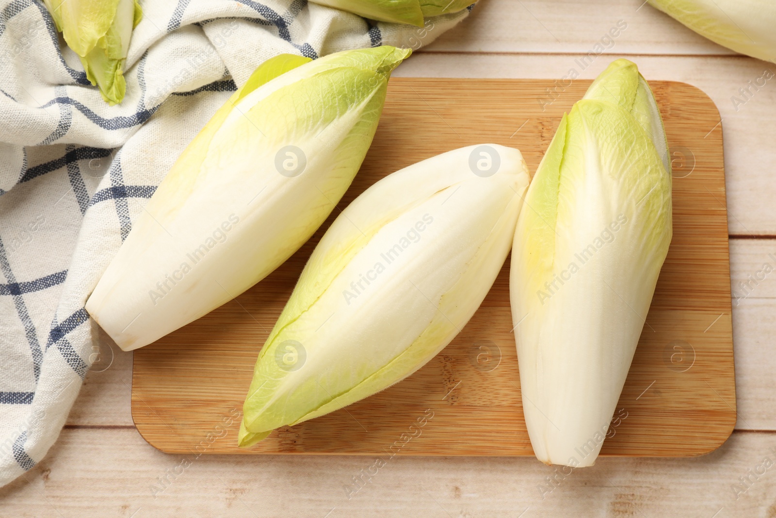 Photo of Raw ripe chicories on wooden table, top view