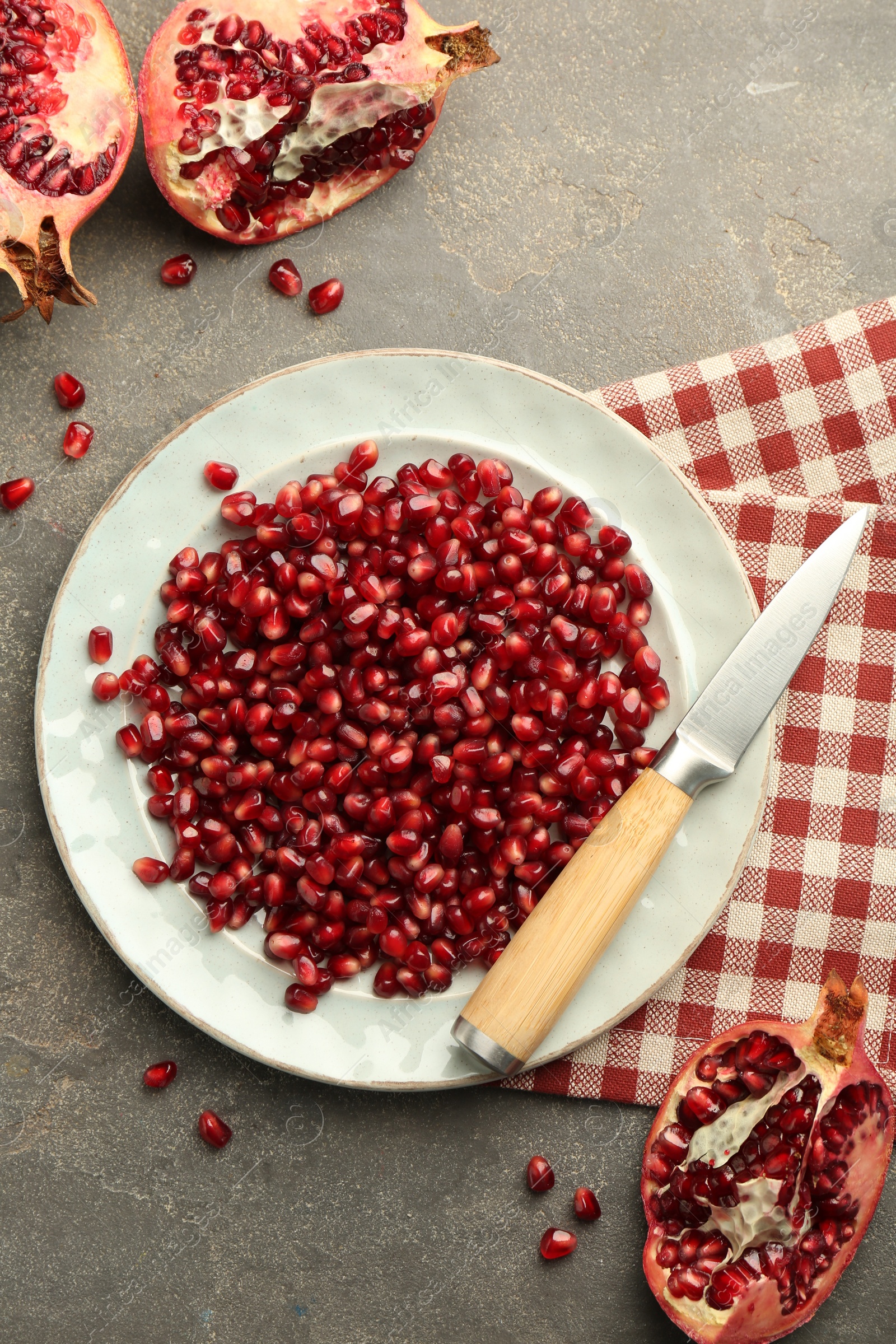 Photo of Tasty ripe pomegranate and grains on grey table, flat lay