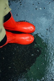 Woman wearing red rubber boots on rainy day, above view