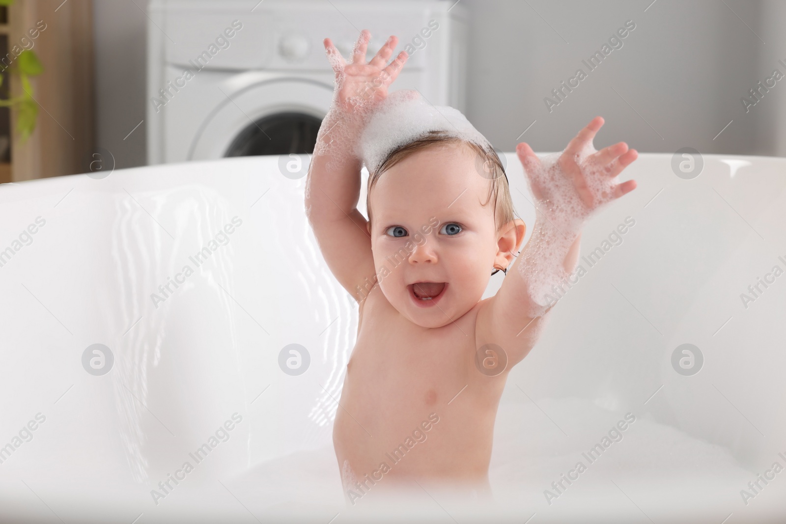 Photo of Cute little baby taking foamy bath at home