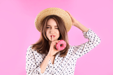 Photo of Beautiful young woman wearing stylish hat with donut on light pink background