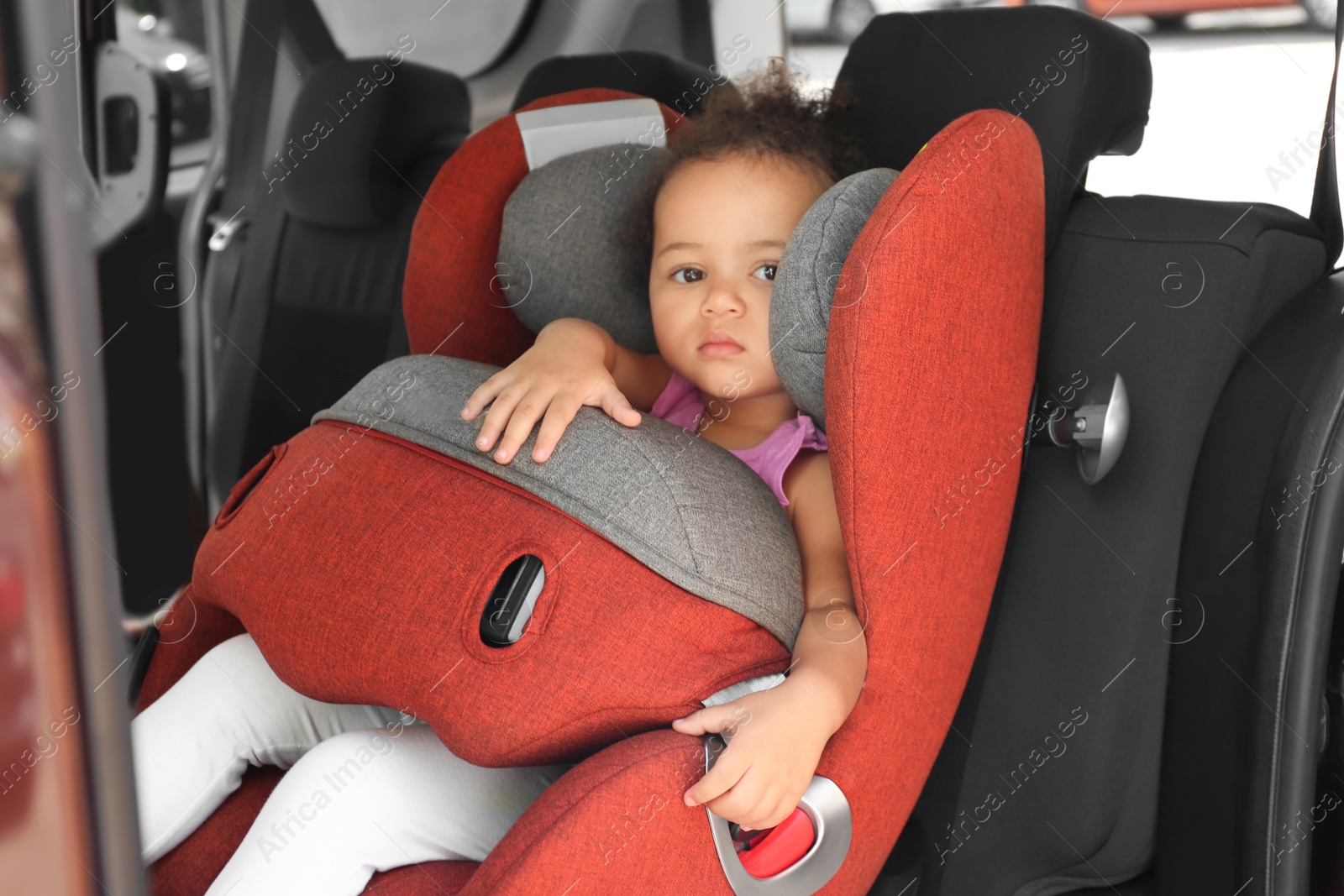 Photo of Little African-American girl in child safety seat inside of car