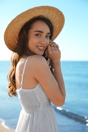 Photo of Happy young woman with beach hat near sea