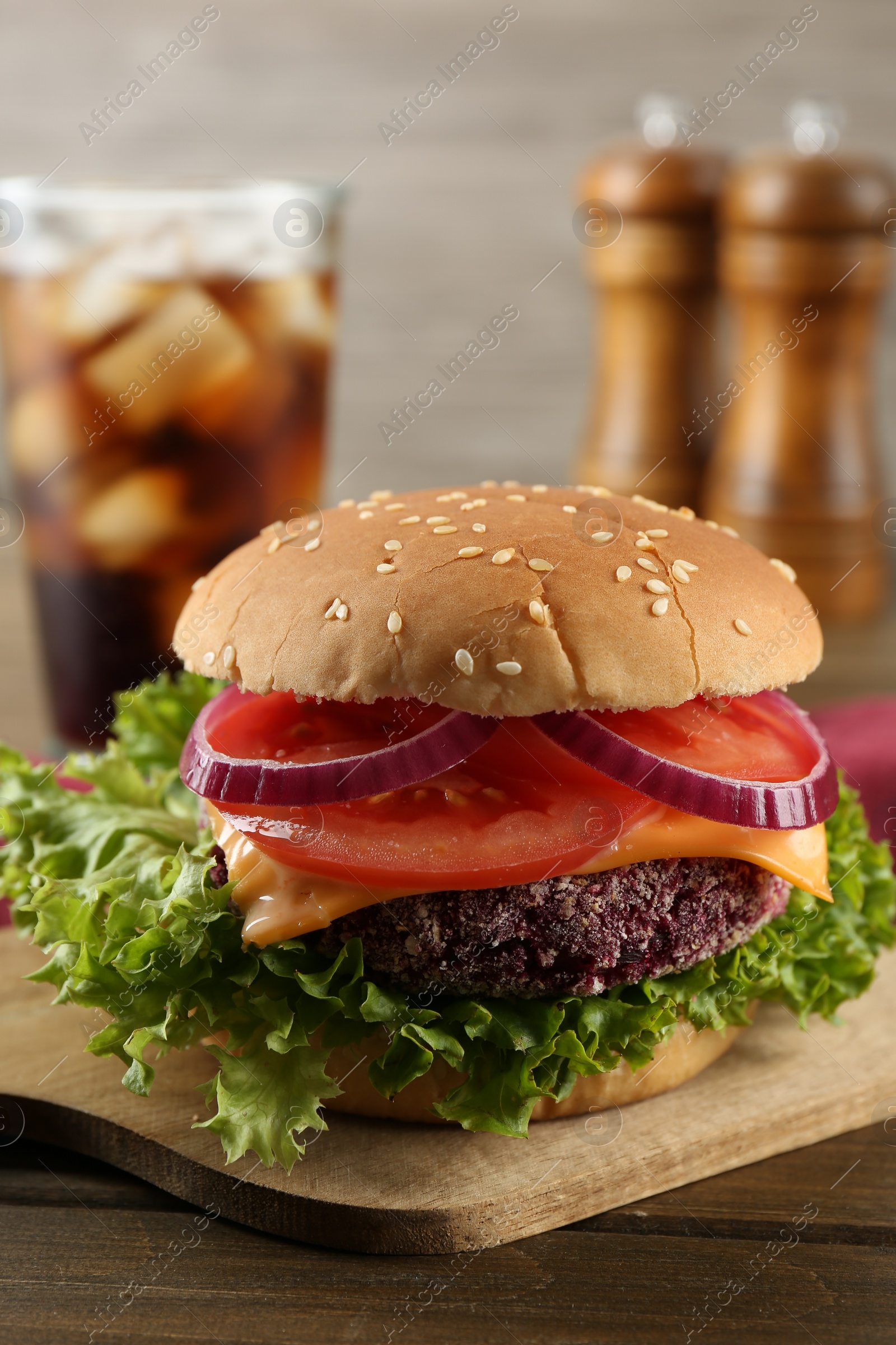 Photo of Tasty vegetarian burger with beet patty and soda drink on wooden table, closeup