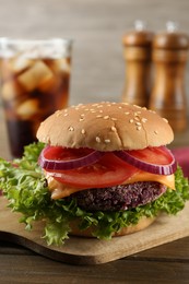 Photo of Tasty vegetarian burger with beet patty and soda drink on wooden table, closeup
