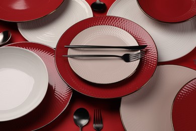 Stylish table setting with cutlery on red background