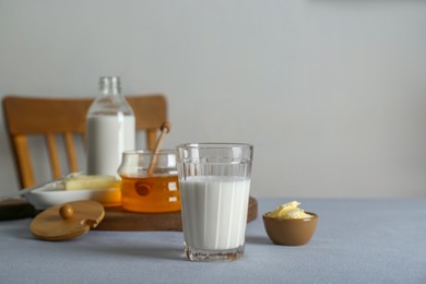 Photo of Glass with milk, honey and butter on grey table, space for text