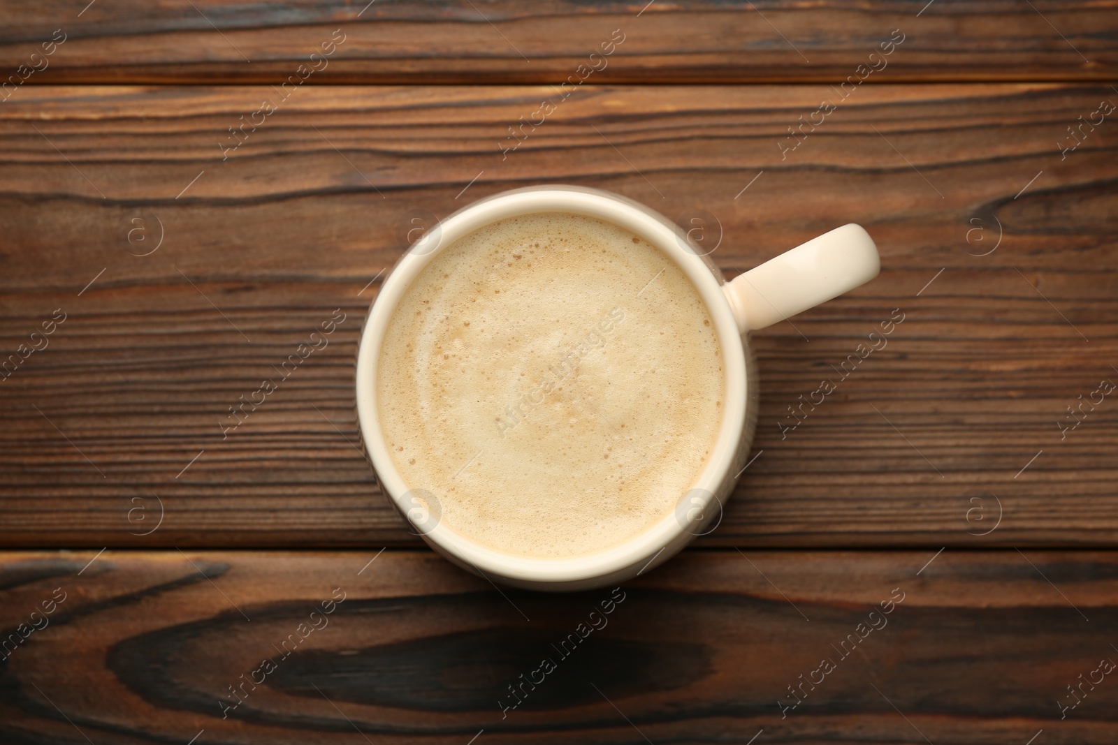 Photo of Cup of aromatic coffee on wooden table, top view