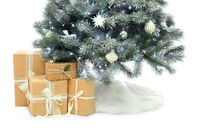 Decorated Christmas tree with faux fur skirt and gift boxes on white background