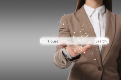 Real estate agent holding virtual search bar with word House on grey background, closeup. Space for text