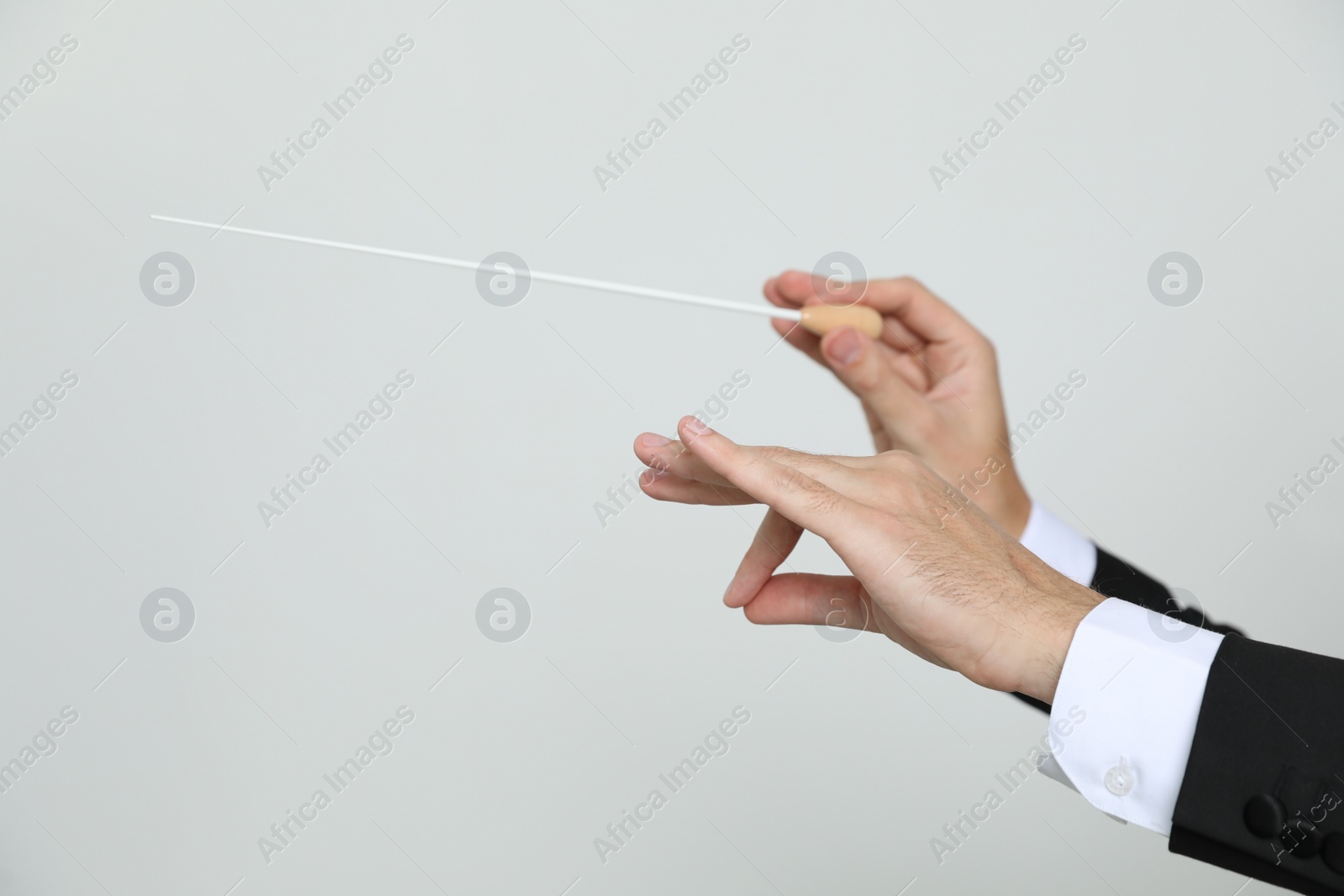 Photo of Professional conductor with baton on light grey background, closeup. Space for text