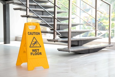 Safety sign with phrase Caution wet floor near stairs. Cleaning service