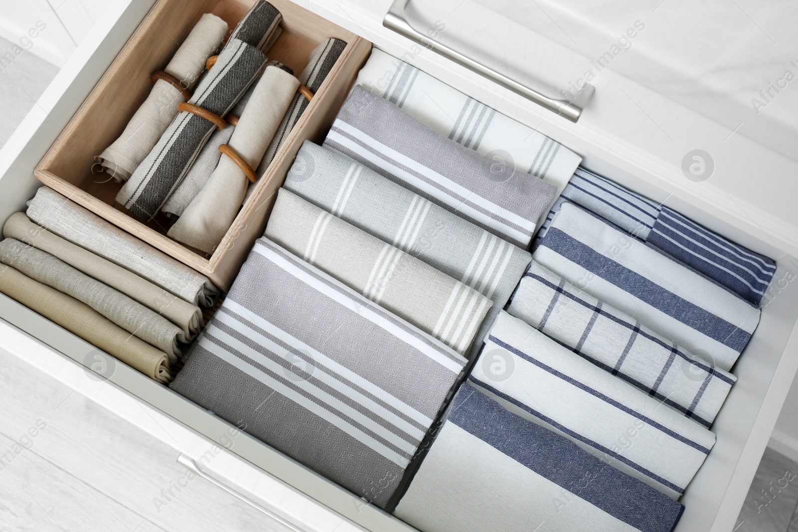 Photo of Open drawer with folded napkins and towels indoors, top view. Order in kitchen