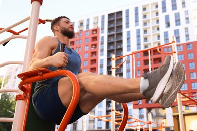 Photo of Man training on abs station, low angle view. Outdoor gym