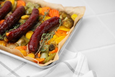 Photo of Baking tray with delicious smoked sausages and vegetables on white table, closeup. Space for text