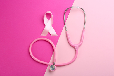 Pink ribbon as breast cancer awareness symbol and stethoscope on color background, flat lay