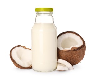 Glass bottle of delicious vegan milk and coconut pieces on white background