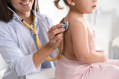 Photo of Pediatrician examining baby with stethoscope in clinic, closeup