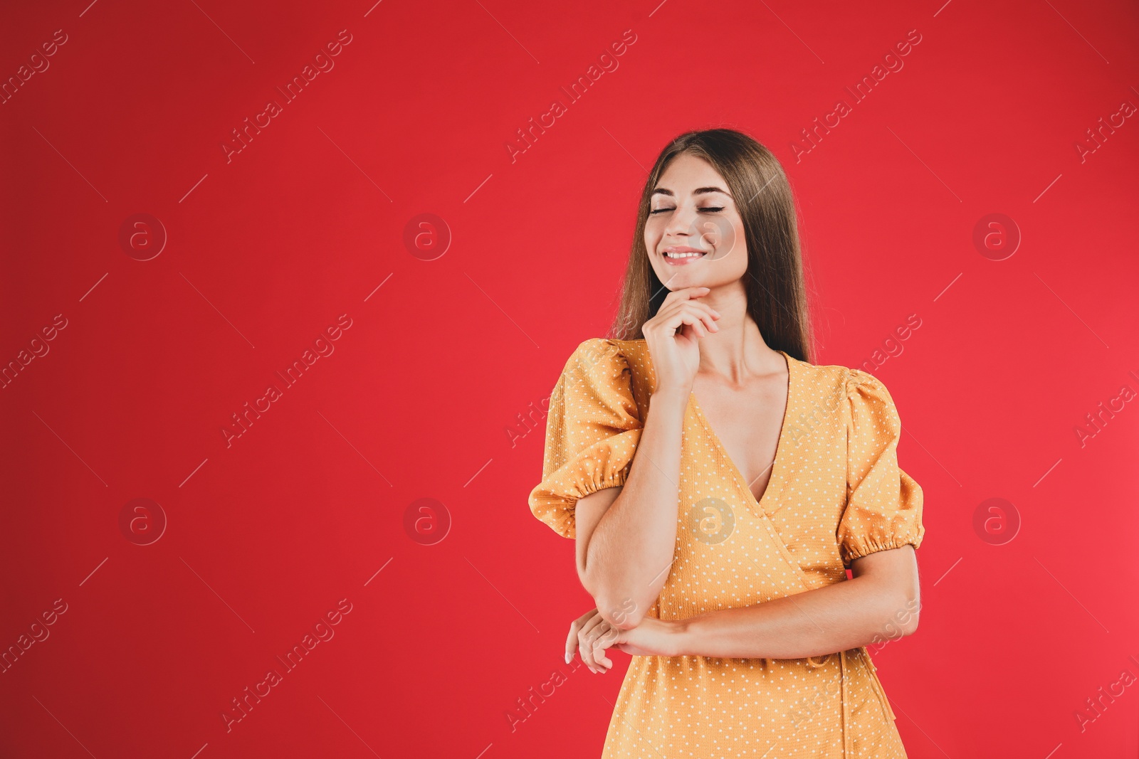 Photo of Young woman wearing stylish yellow dress on red background. Space for text