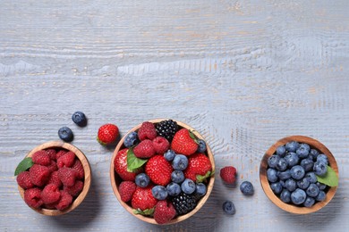 Photo of Different fresh ripe berries on light grey wooden table, flat lay. Space for text