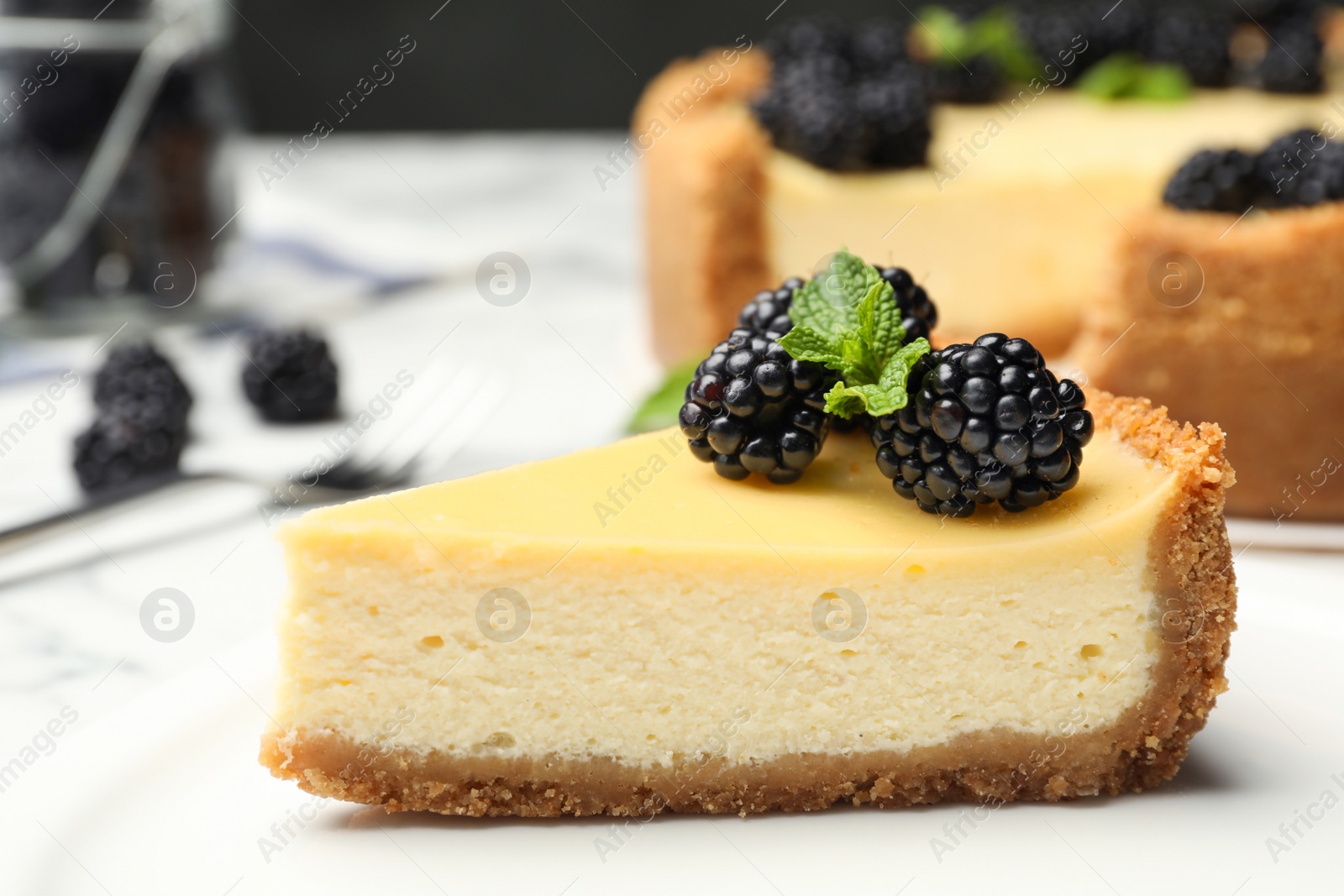 Photo of Piece of delicious cheesecake decorated with blackberries on table