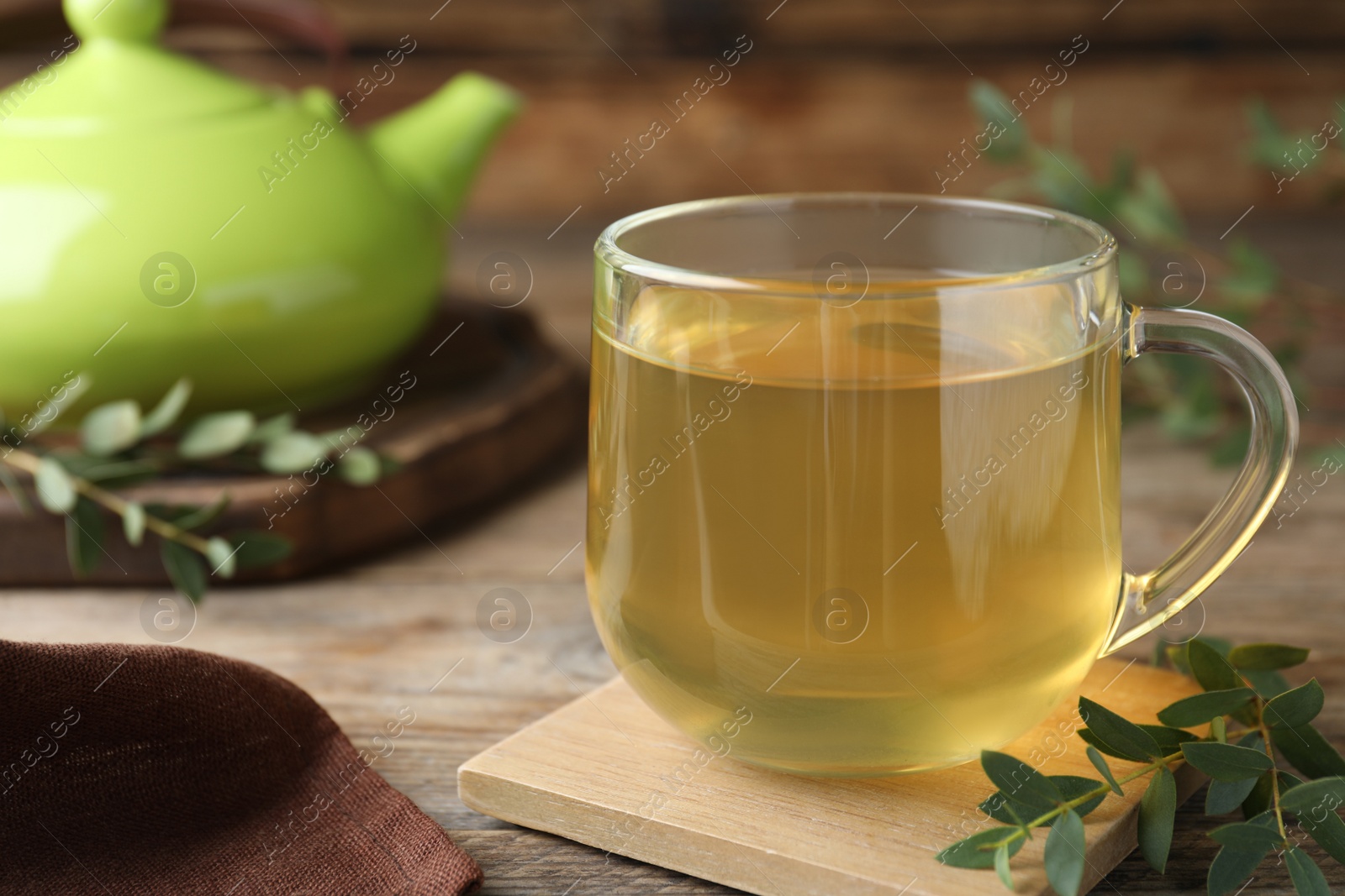 Photo of Glass cup of aromatic eucalyptus tea on wooden table, closeup