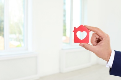 Photo of Real estate agent holding house model on blurred background, closeup