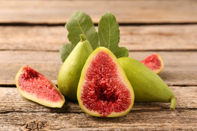 Photo of Cut and whole green figs on wooden table, closeup