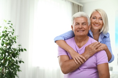 Photo of Portrait of happy senior couple at home. Space for text