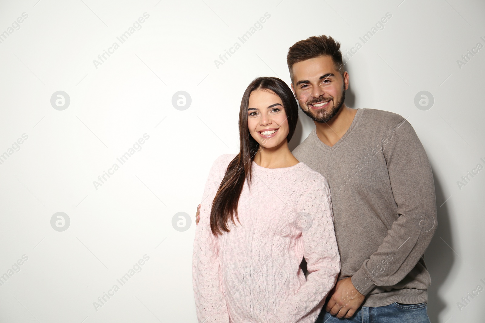 Image of Lovely couple in warm sweaters on light background. Space for text