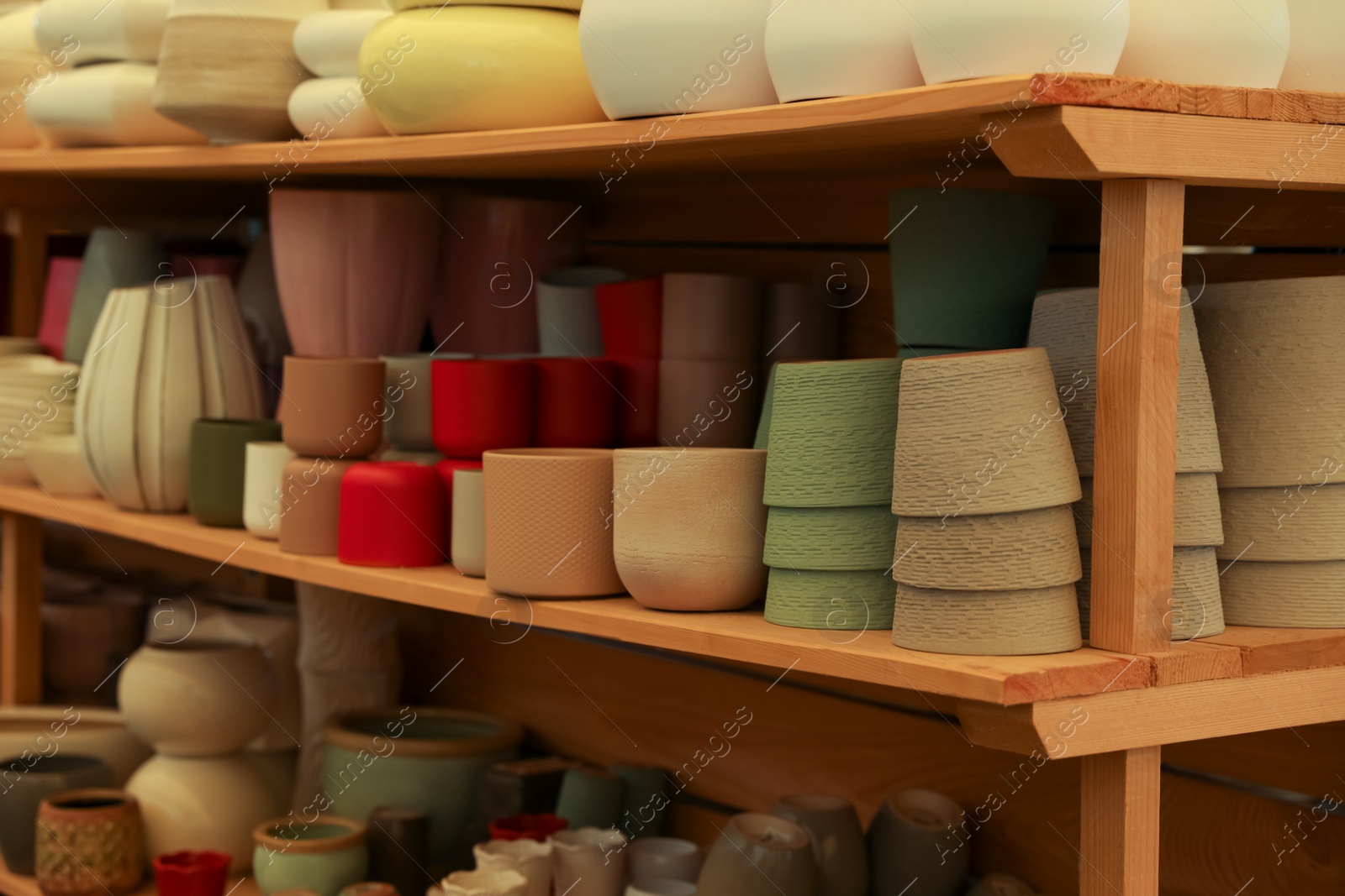 Photo of Many different flower pots on shelves in gardening shop