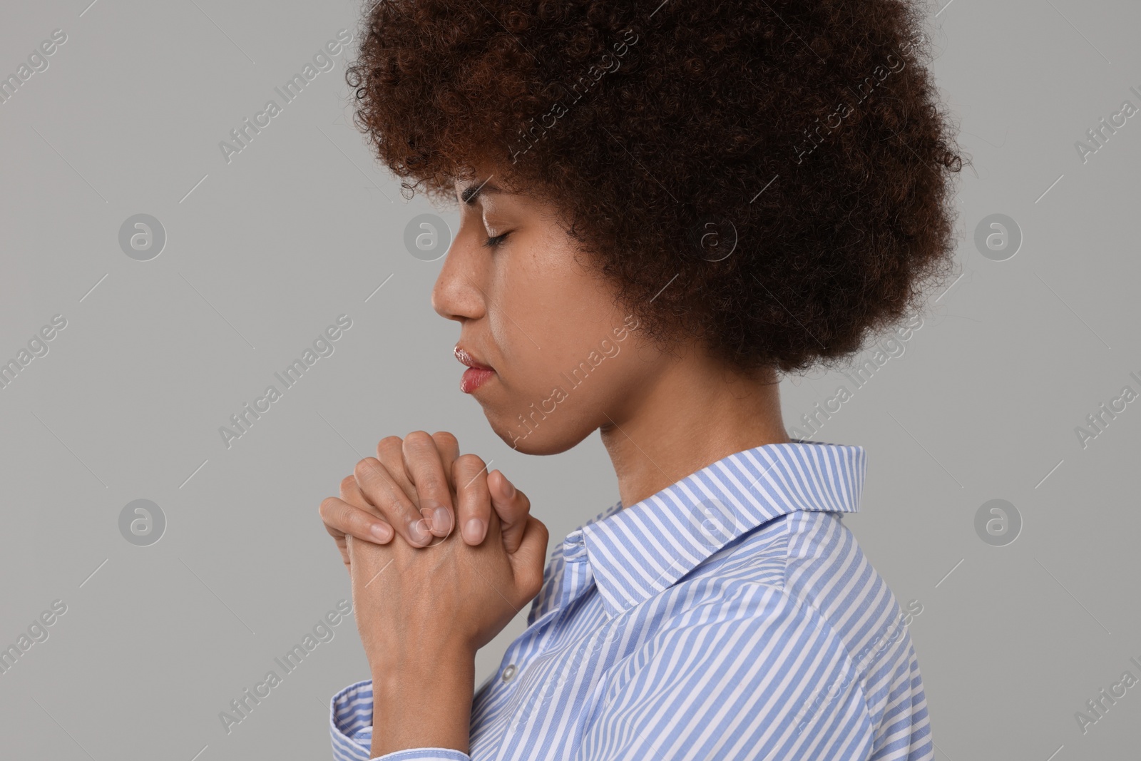 Photo of Woman with clasped hands praying to God on grey background