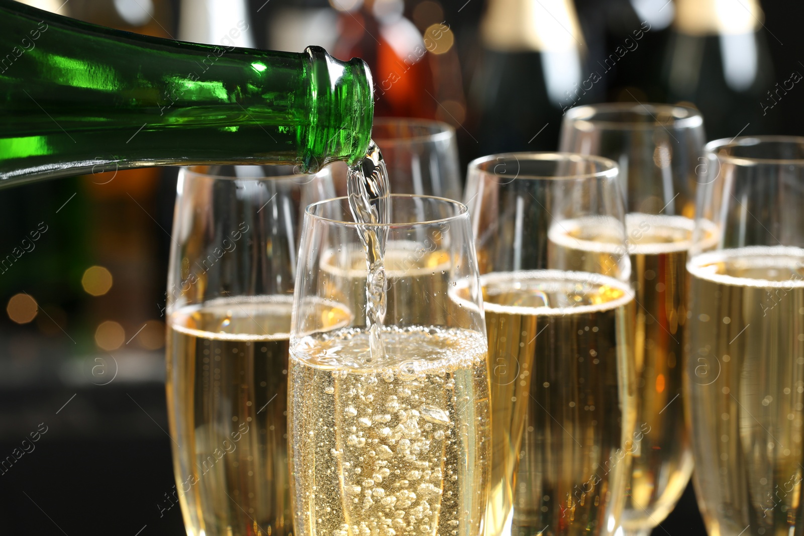 Photo of Pouring champagne into glasses on blurred background, closeup