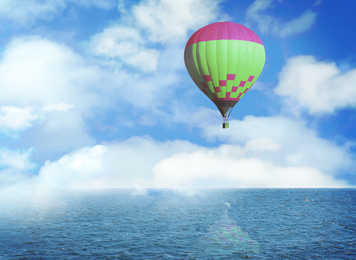 Image of Dream world. Hot air balloon in blue sky with clouds over sea