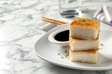 Photo of Tasty turnip cake served on white marble table. Space for text