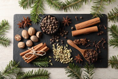 Photo of Different spices and fir branches on wooden table, flat lay