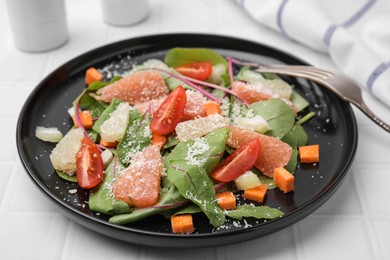 Delicious salad with pomelo, tomatoes and cheese on white tiled table