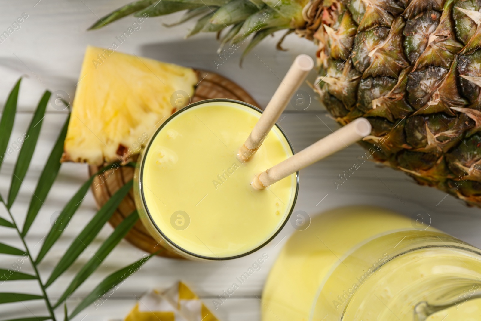 Photo of Tasty pineapple smoothie and fruit on white wooden table, flat lay