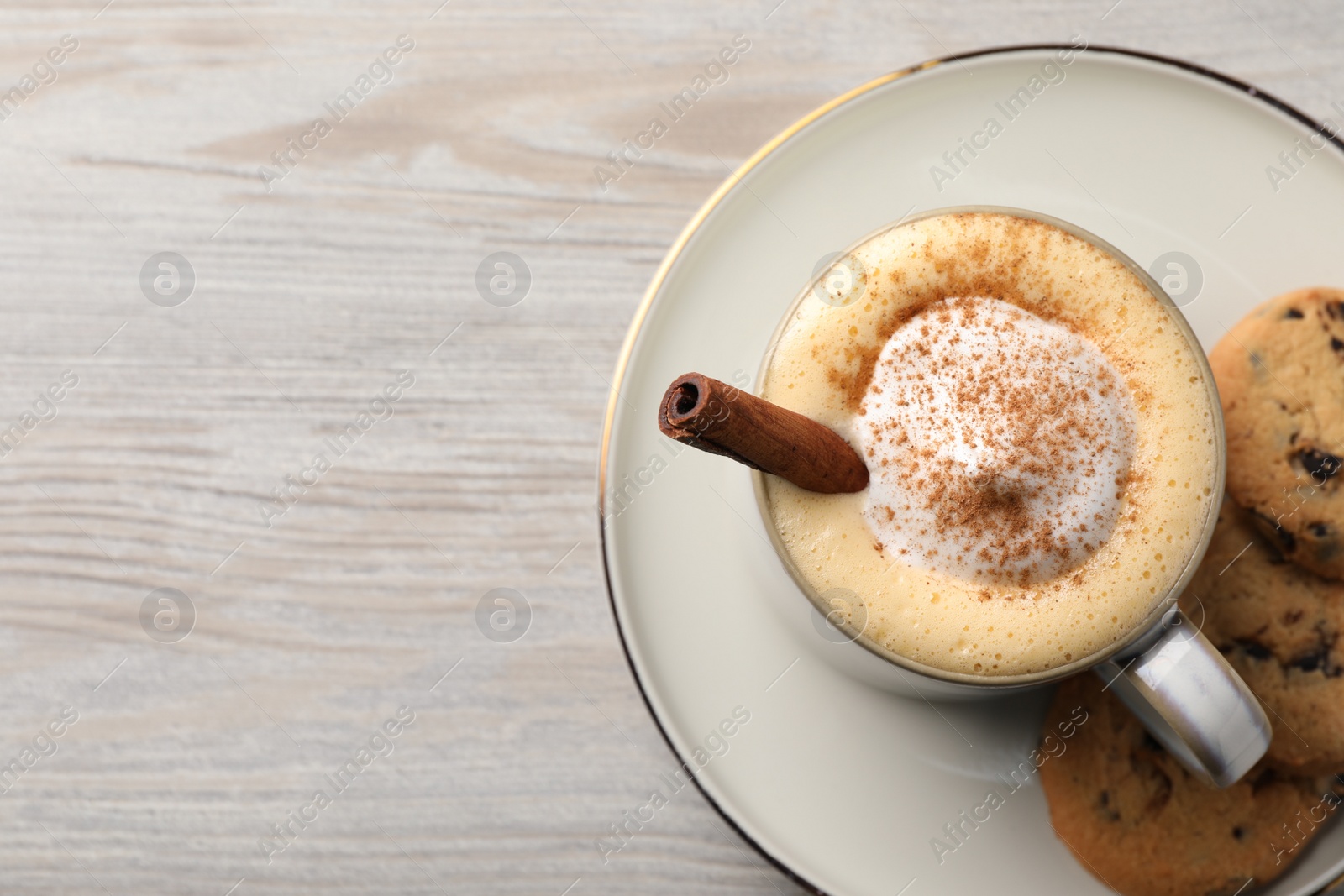 Photo of Cup of delicious eggnog with cinnamon on wooden table, top view. Space for text